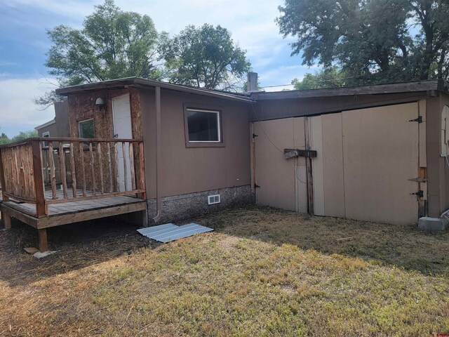 back of property featuring a yard and a wooden deck