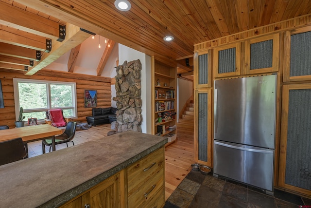 kitchen featuring stainless steel refrigerator, lofted ceiling with beams, rustic walls, wood ceiling, and dark wood-type flooring