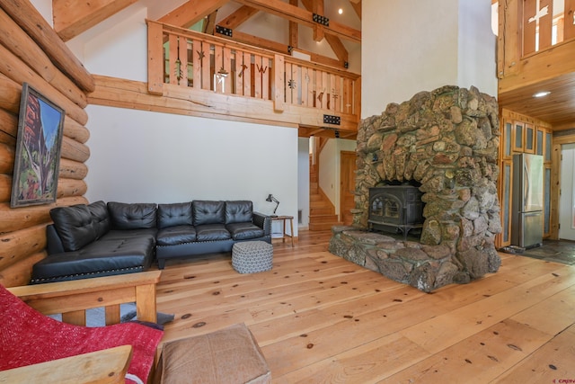 living room with wood-type flooring, high vaulted ceiling, a wood stove, beamed ceiling, and log walls