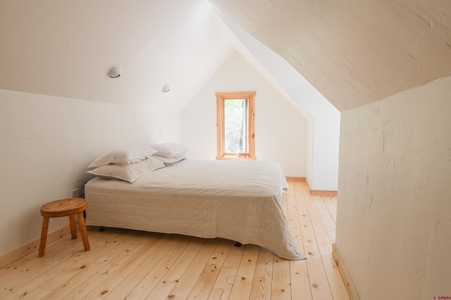 bedroom with lofted ceiling and wood-type flooring