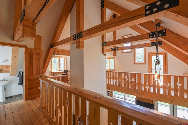 corridor with beamed ceiling, high vaulted ceiling, light hardwood / wood-style floors, and a wealth of natural light