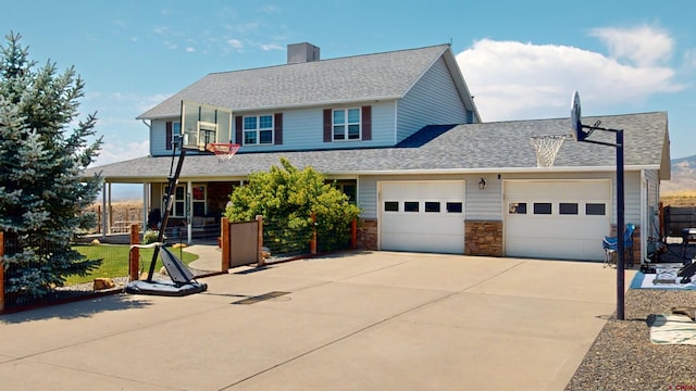 view of front of house featuring driveway, stone siding, roof with shingles, an attached garage, and covered porch