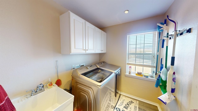 laundry room with cabinet space, a sink, separate washer and dryer, wood finished floors, and baseboards