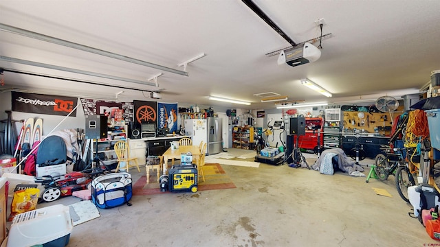 garage with stainless steel fridge, a workshop area, and a garage door opener