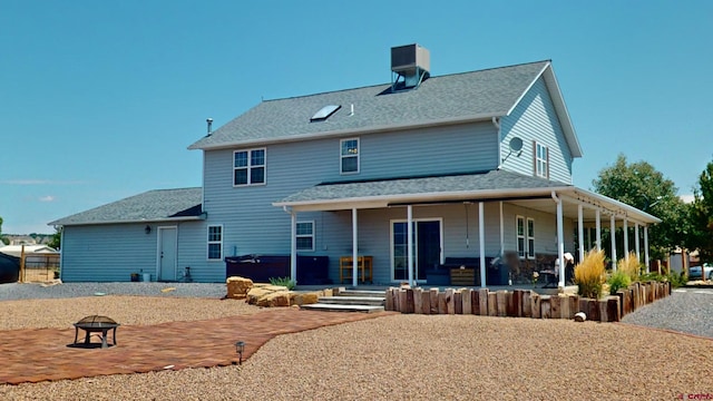 rear view of property featuring a fire pit, central AC, a patio area, and a hot tub