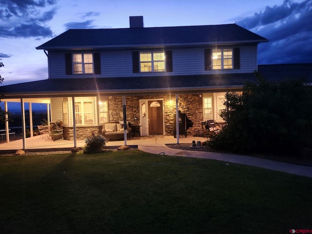 view of front of home featuring stone siding, a patio, a chimney, and a front lawn