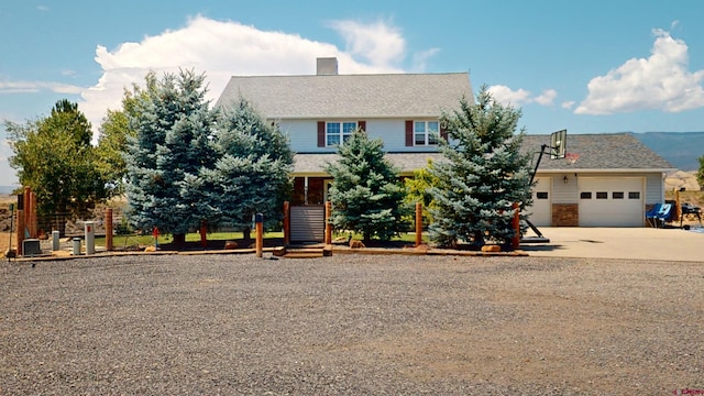 view of front facade featuring driveway, a garage, a chimney, and fence