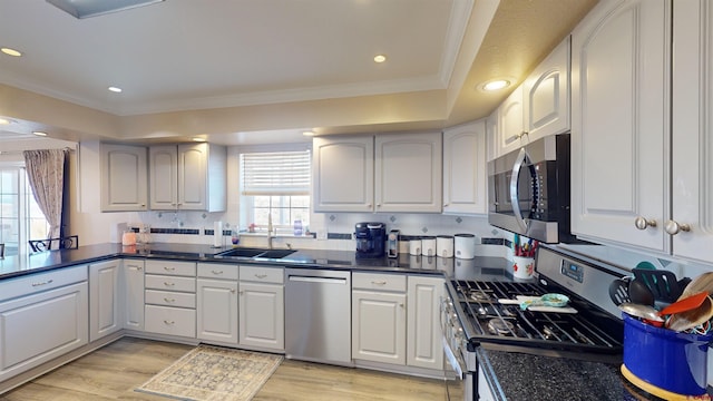 kitchen featuring appliances with stainless steel finishes, light wood-style floors, a sink, and ornamental molding