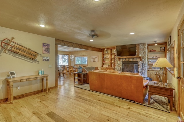 living room featuring a textured ceiling, light wood-type flooring, a fireplace, and baseboards