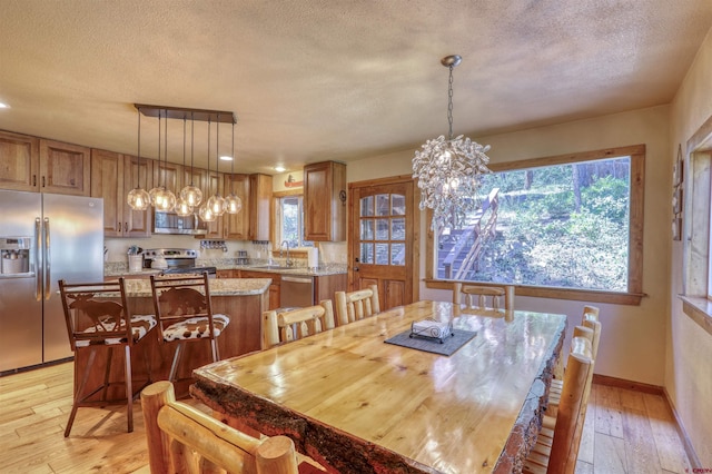 dining space with light wood finished floors, plenty of natural light, and a textured ceiling