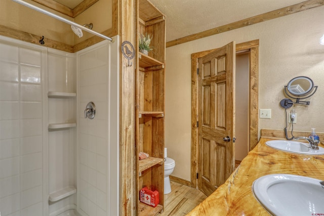 full bathroom with toilet, a stall shower, a sink, and wood finished floors