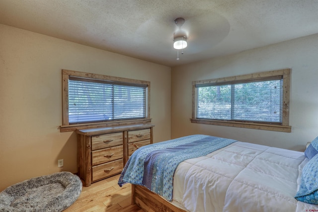 bedroom with a ceiling fan, light wood-style flooring, and a textured ceiling