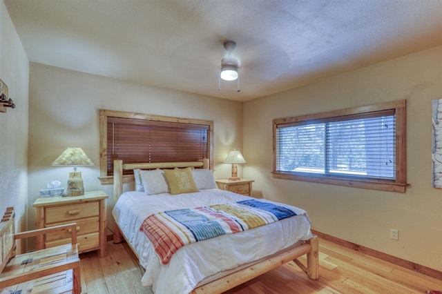 bedroom featuring light wood-type flooring, baseboards, and a ceiling fan