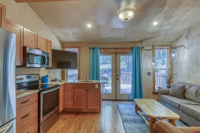 kitchen featuring french doors, light countertops, appliances with stainless steel finishes, a sink, and light wood-type flooring