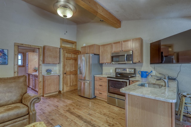 kitchen with stainless steel appliances, light brown cabinetry, a sink, light stone countertops, and a peninsula