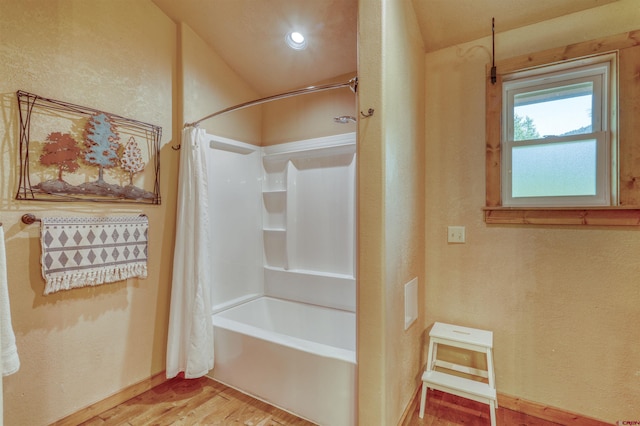 full bath featuring a textured wall, baseboards, shower / tub combo with curtain, and wood finished floors