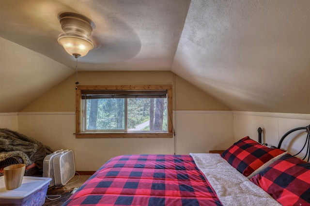 bedroom featuring a ceiling fan, lofted ceiling, and a textured ceiling