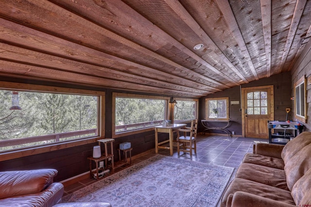 unfurnished living room featuring lofted ceiling, wooden ceiling, and dark tile patterned floors