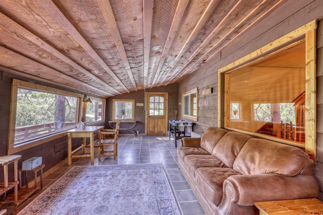 unfurnished living room with vaulted ceiling, dark tile patterned flooring, wood walls, and wooden ceiling