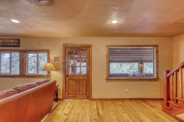 entrance foyer with stairway, light wood-style flooring, baseboards, and a textured ceiling