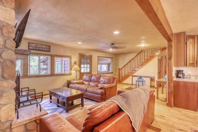 living room with recessed lighting, light wood-style flooring, stairway, a textured ceiling, and baseboards