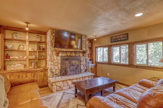 living room with a wealth of natural light, a fireplace, light wood finished floors, and a textured ceiling