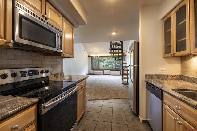 kitchen with appliances with stainless steel finishes, dark carpet, decorative backsplash, and dark stone counters