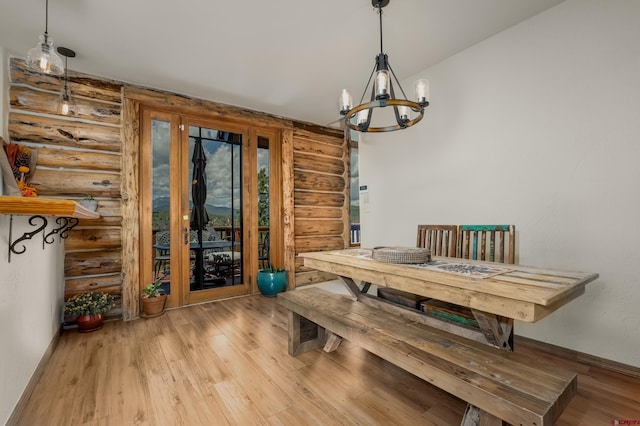 dining area featuring a notable chandelier, light hardwood / wood-style flooring, and rustic walls