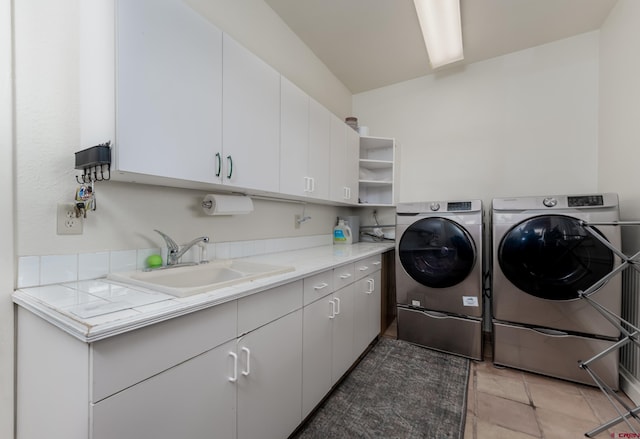 clothes washing area with cabinets, sink, washing machine and dryer, and light tile patterned floors