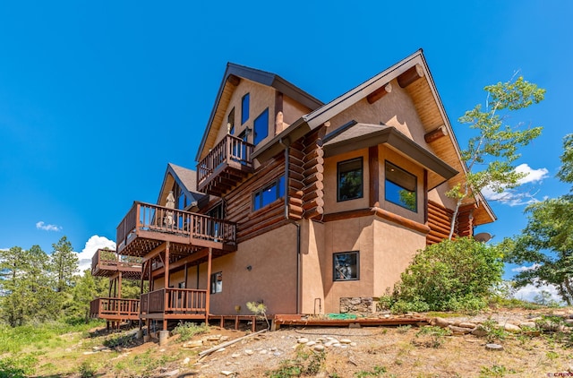 rear view of house featuring a wooden deck and a balcony