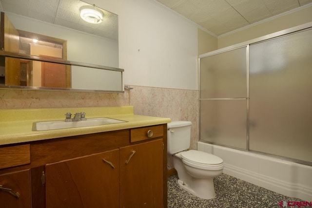 full bathroom featuring toilet, shower / bath combination with glass door, tile walls, ornamental molding, and vanity