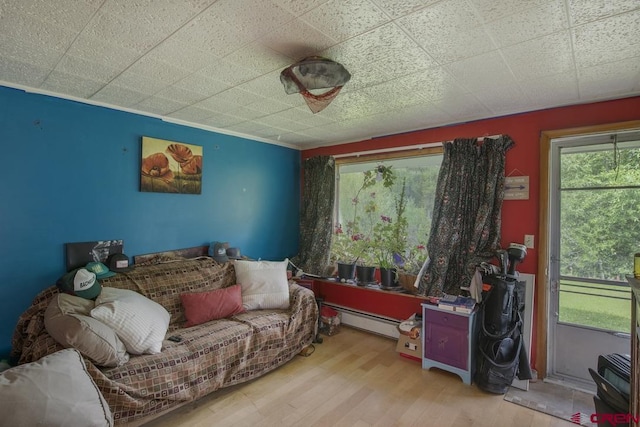 sitting room featuring a baseboard heating unit and wood-type flooring