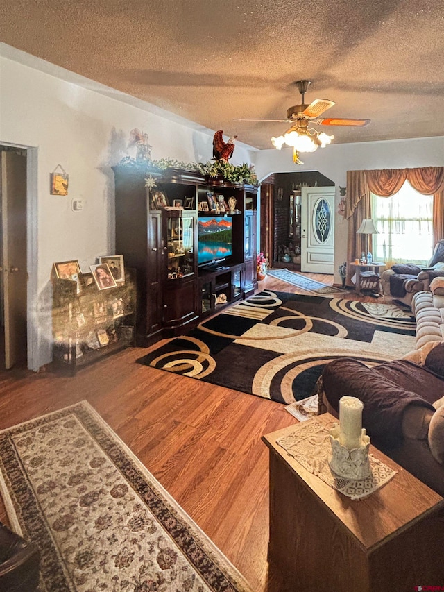 living room with ceiling fan, wood-type flooring, and a textured ceiling