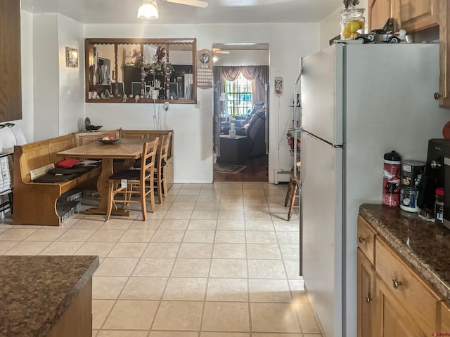 tiled dining space featuring ceiling fan and baseboard heating