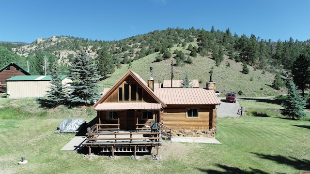 rear view of house with a mountain view, an outdoor structure, and a lawn