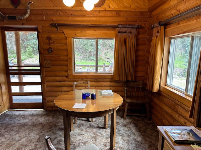 dining space with dark carpet, log walls, and plenty of natural light