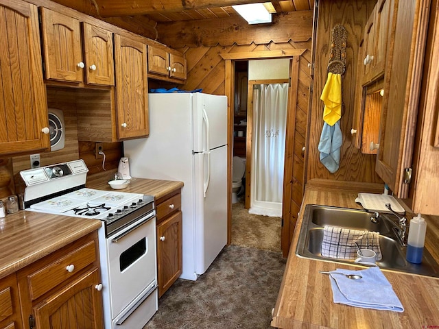 kitchen with beam ceiling, dark colored carpet, wood ceiling, white gas range oven, and sink