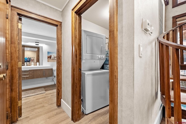 clothes washing area featuring light hardwood / wood-style flooring and stacked washing maching and dryer