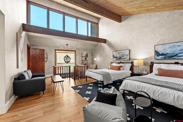 bedroom with beam ceiling, a towering ceiling, wood ceiling, and light hardwood / wood-style floors