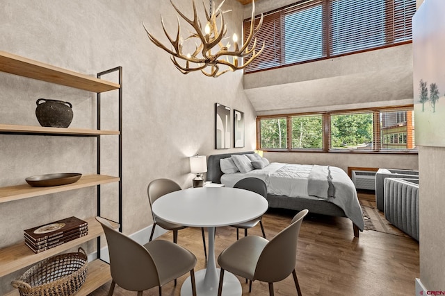 bedroom featuring a towering ceiling, hardwood / wood-style floors, and a notable chandelier