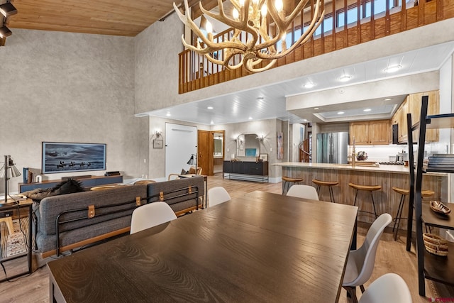 dining space featuring wood ceiling, a towering ceiling, light hardwood / wood-style floors, and a chandelier