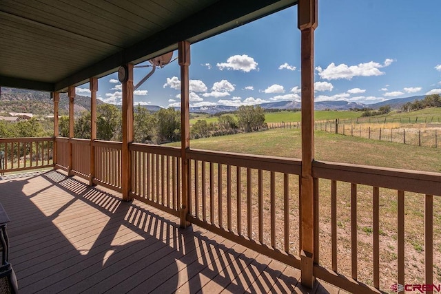 wooden deck featuring a rural view, a mountain view, and a yard