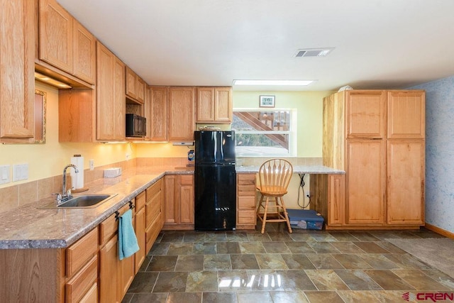 kitchen with sink, light brown cabinetry, light stone counters, and black appliances