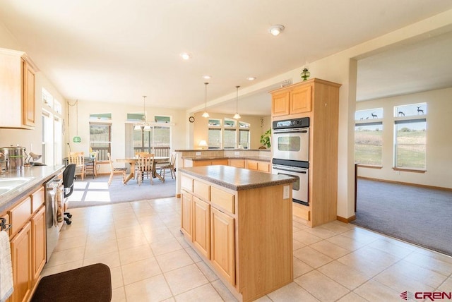 kitchen with stainless steel appliances, a center island, pendant lighting, and light brown cabinetry