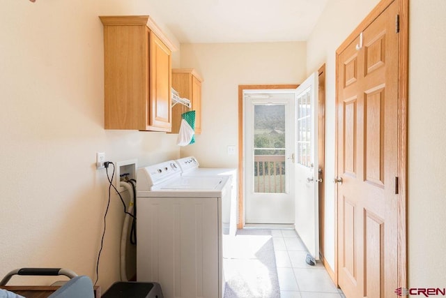 laundry room with cabinets, light tile patterned floors, and washing machine and clothes dryer