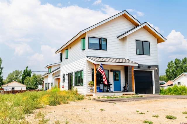 view of front of property with covered porch, a standing seam roof, metal roof, a garage, and driveway