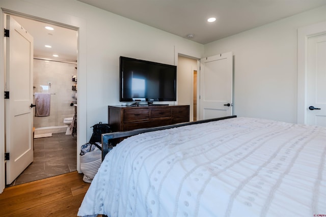 bedroom with recessed lighting, connected bathroom, and wood finished floors