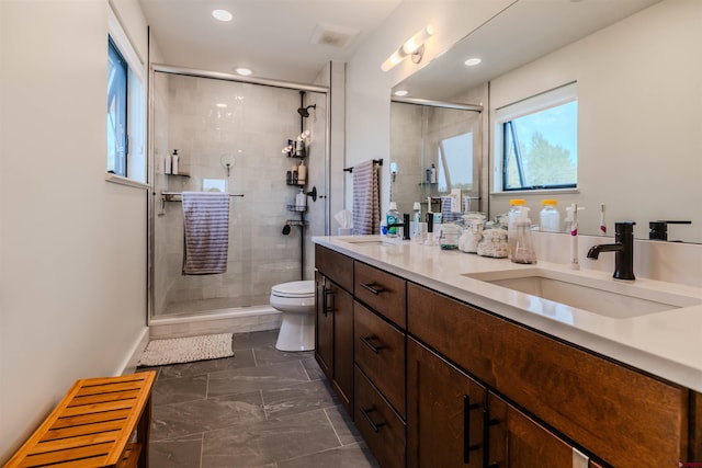 bathroom featuring double vanity, a sink, toilet, and a shower stall