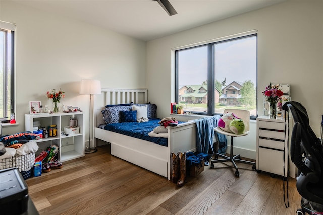 bedroom featuring ceiling fan, multiple windows, and wood finished floors