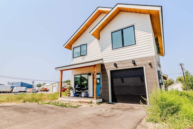 contemporary house with driveway, a porch, and an attached garage